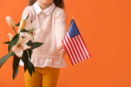 Little girl with USA flag and flowers on color background. memorial day celebration