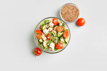 Bowl with healthy vegetable salad and flax seeds on light backgroundの写真素材