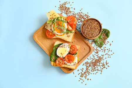 Board with tasty toasts on color background
