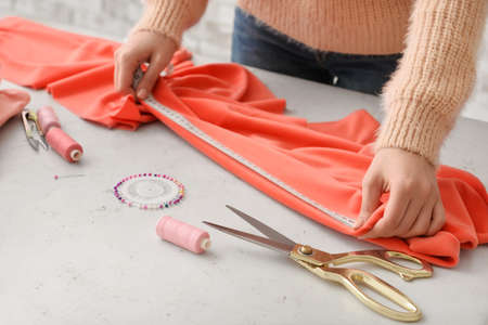 Young woman measuring fabric in studio
