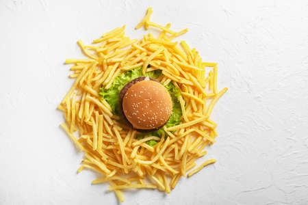 Tasty french fries and burger on light backgroundの写真素材