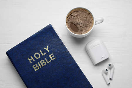 Holy Bible, cup of coffee and earphones on light wooden backgroundの写真素材