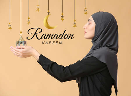Praying Muslim woman with lamp on color background. ramadan celebrationの写真素材