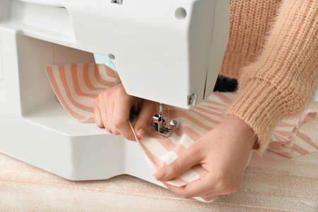 Young woman sewing clothes at table