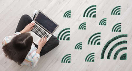 Young woman with laptop using wi-fi at home, top view