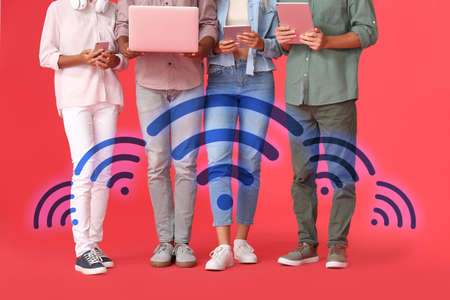 Teenagers with different devices using wi-fi on color backgroundの写真素材