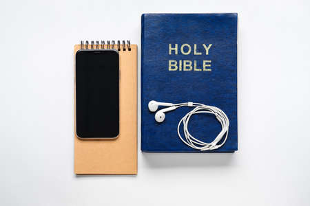 Holy Bible, mobile phone and earphones on white backgroundの写真素材