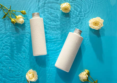 Bottle of cosmetic product and roses in water on color background