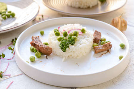 Plate with tasty rice, green peas on light backgroundの写真素材
