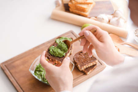 Woman making tasty toasts with pesto sauce on table, closeupの写真素材