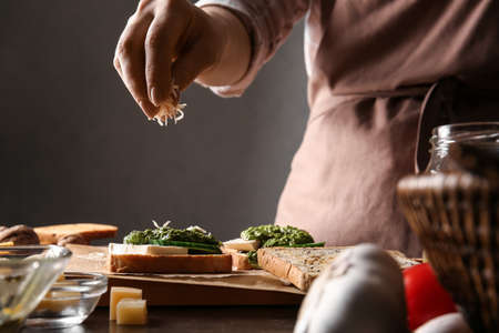 Woman decorating tasty toasts with cheese on table, closeupの写真素材