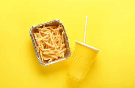 Box with tasty french fries and cup of beverage on color backgroundの写真素材