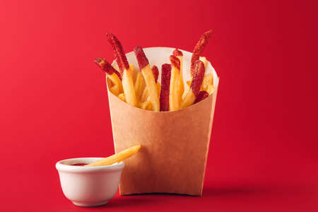Creative composition with tasty french fries in paper box on color backgroundの写真素材