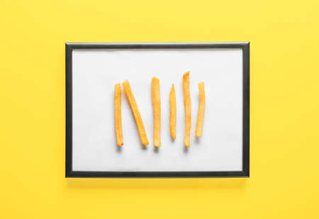 Creative composition with frame and tasty french fries on color background