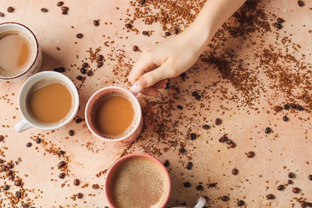 Female hand and cups of coffee on color backgroundの写真素材