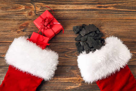Christmas socks with coal and gift boxes on wooden background
