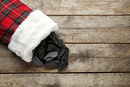 Christmas sock with coal on wooden background