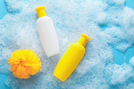Bottles of cosmetic products and sponge with foam on color backgroundの写真素材