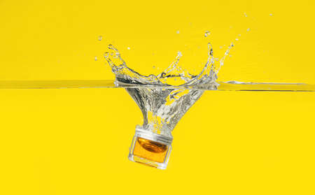 Jar of cosmetic product in water on color background
