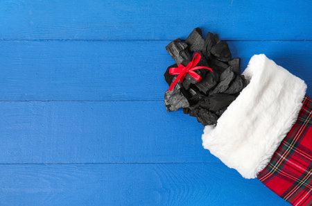 Christmas sock with coal on color background
