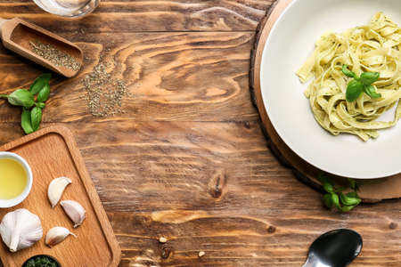 Plate with tasty pesto pasta and ingredients on tableの写真素材