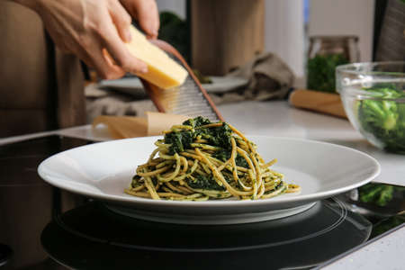 Plate with tasty pasta and spinach on stove in kitchen