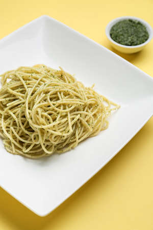 Plate with tasty pesto pasta on color background