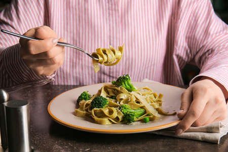 Woman eating healthy pasta with vegetables at tableの写真素材