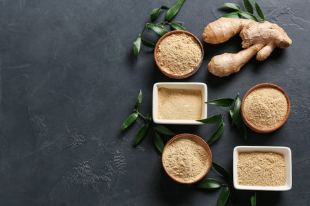 Bowls with ginger powder on dark background
