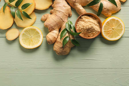 Ginger powder, roots and lemons on color wooden backgroundの写真素材
