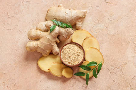 Bowl with ginger powder and roots on color backgroundの写真素材