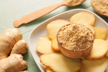 Plate with fresh and dried ginger on color wooden background, closeup
