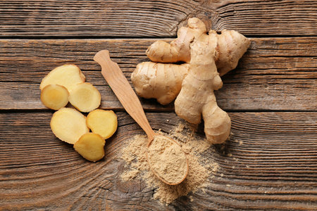 Spoon with ginger powder on wooden table