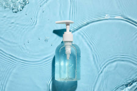 Bottle of cosmetic product in water on color backgroundの写真素材