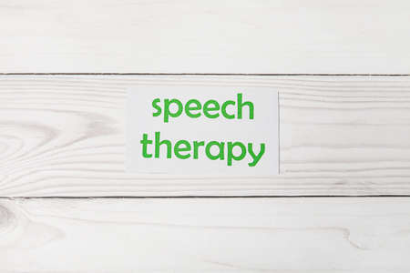 Paper with text SPEECH THERAPY on white wooden backgroundの写真素材