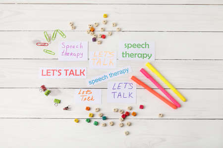 Paper pieces with text LET'S TALK and SPEECH THERAPY on white wooden backgroundの写真素材