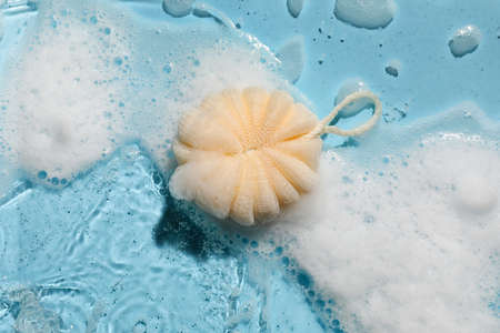Loofah with foam in water on color backgroundの写真素材
