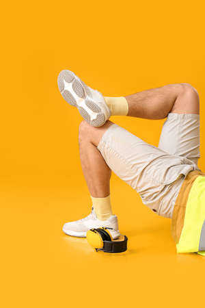 Lying male worker with headphones on yellow background