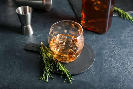 Glass of cold whiskey on dark background