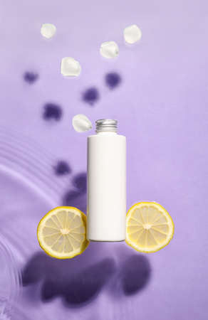Bottle of cosmetic product and lemon in water on color background