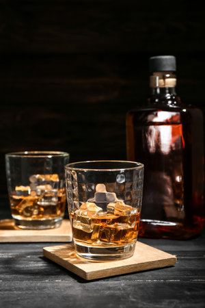 Bottle and glasses of cold whiskey on dark wooden backgroundの写真素材