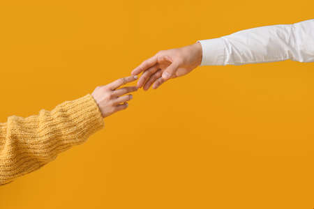 Hands of couple on yellow background