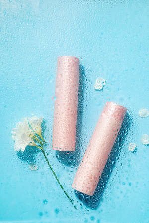 Bottles of cosmetic products and flowers in water on color backgroundの写真素材