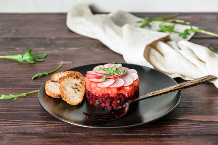 Plate of delicious tartare salad on wooden table