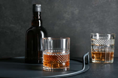 Bottle and glasses of whiskey on dark background