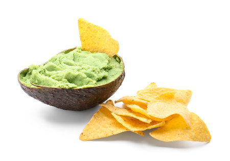 Tasty guacamole in avocado peel and nachos on white backgroundの写真素材