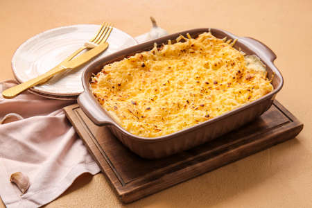 Baking dish with tasty green lasagna on color background