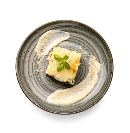 Plate with piece of tasty green lasagna and sauce on white backgroundの写真素材