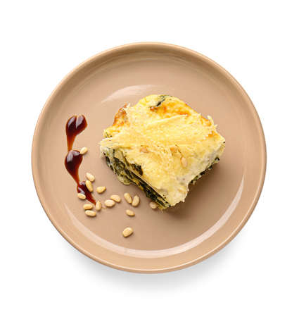 Plate with piece of tasty green lasagna and sauce on white backgroundの写真素材