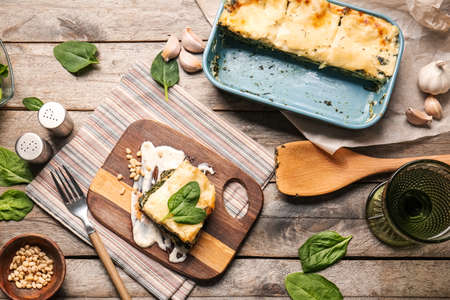 Board with tasty green lasagna and ingredients on wooden backgroundの写真素材